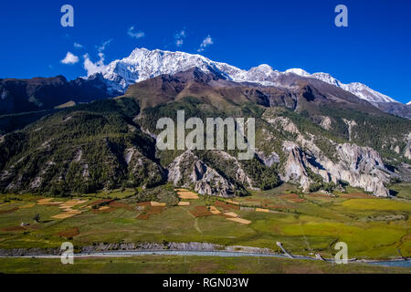 Panoramic aerial view on the agricultural countryside of the Upper Marsyangdi valley, the snow covered summit of Annapurna 3 in the distance Stock Photo