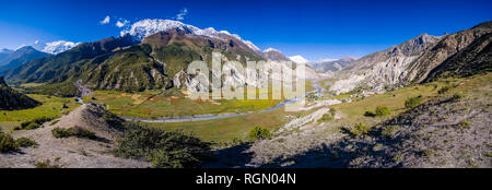 Panoramic aerial view on the agricultural countryside of the Upper Marsyangdi valley, the snow covered summits of the Annapurna range in the distance