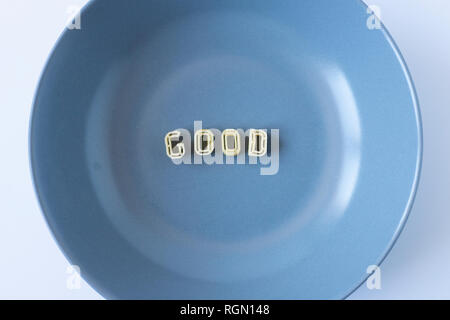 The word 'good' composed with real pasta letters in a blue dish.