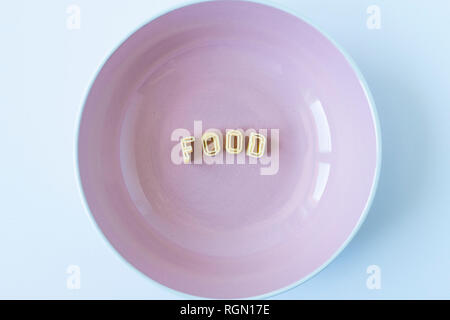 The word 'food' composed with real pasta letters in a pink dish. Stock Photo