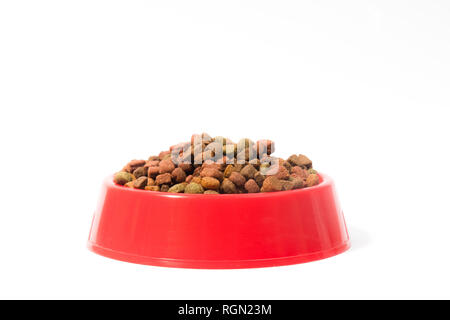 Red bowl with dry animal food for cats or dogs on white background with space for text Stock Photo