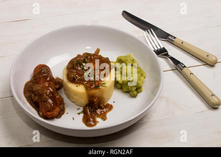 very typical irish dish, mashed potato, onion gravey, grilled sausages, mushy peas and chopped rosemary Stock Photo