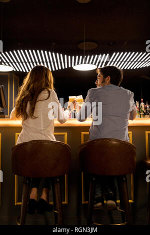 Rear view of couple clinking beer glasses in a bar Stock Photo