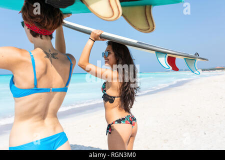 Friends going to surf, carrying surfboards on top of heads Stock Photo