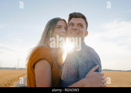 Happy affectionate young couple in backlight in rural landscape Stock Photo