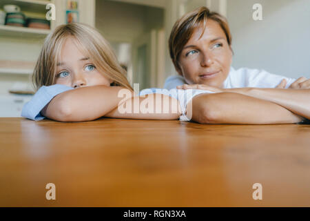 Mother and daughter leaning on kitchen table at home Stock Photo