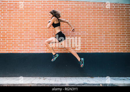Fit young woman running an jumping in park Stock Photo