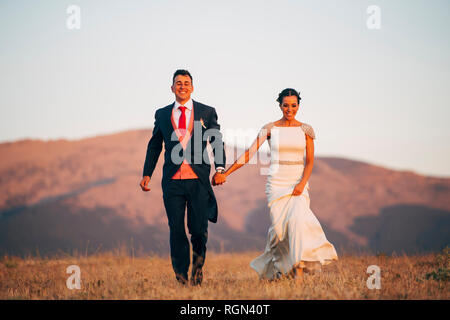 Happy bride and groom walking in mountains Stock Photo