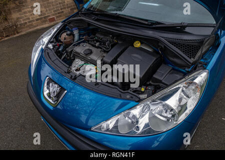 The open bonnet hood showing a Peugeot 207 car engine in England Stock Photo