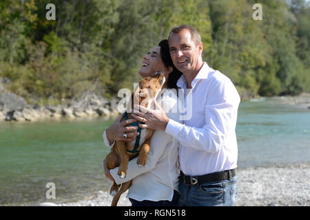 Mature couple with a dog at the river Isar, Upper Bavaria, Germany Stock Photo