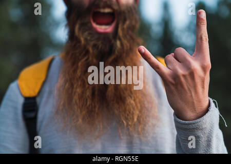 Close-up of screaming man with beard making horn sign Stock Photo