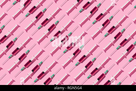 Multiple syringes organized in a pattern over pink background Stock Photo