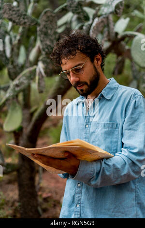 Young man standing in nature, looking at map Stock Photo
