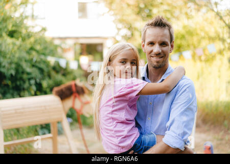 Portrait of smiling father carrying daughter in garden Stock Photo