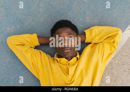 Young black man lying on floor, with hands behind head Stock Photo
