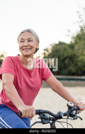 Portrait of smiling senior woman riding bicycle Stock Photo