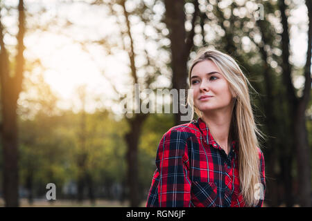 Portrait of young woman wearing plaid shirt in nature Stock Photo