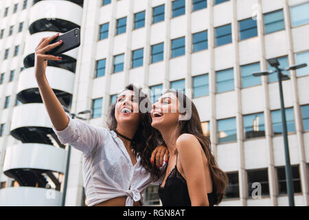 Laughing friends taking selfie with cell phone Stock Photo