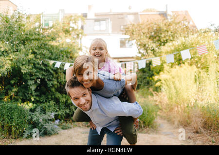 Happy father carrying family piggyback in garden Stock Photo
