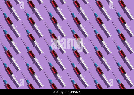 Multiple syringes organized in a pattern over purple background Stock Photo