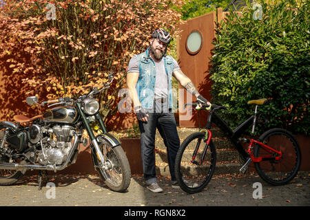 Portrait of man switching from motorbike to bicycle Stock Photo