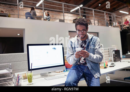 Young man working in creative start-up company, using smartphone Stock Photo