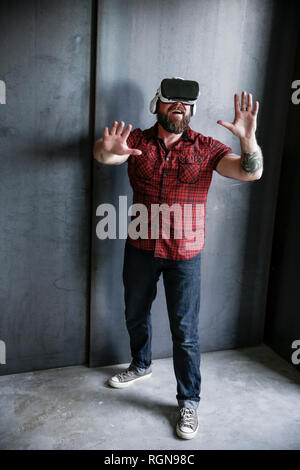 Excited bearded man wearing VR glasses Stock Photo