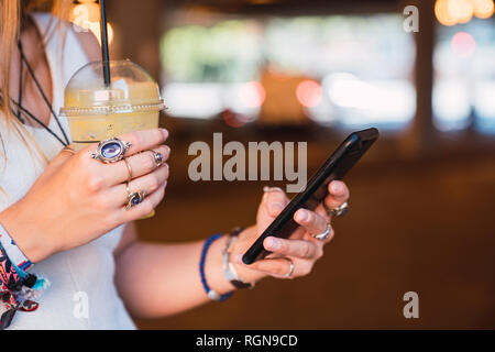 Young woman using smartphone and drinking juice Stock Photo