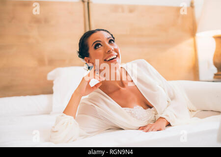 Happy woman lying on bed looking up Stock Photo