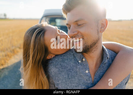 Affectionate young couple at camper van in rural landscape Stock Photo