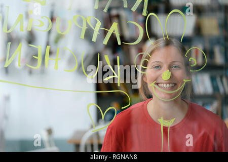 Portrait of happy young woman behind windowpane in a cafe Stock Photo