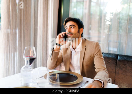 Man sitting at table in a restaurant talking on cell phone Stock Photo