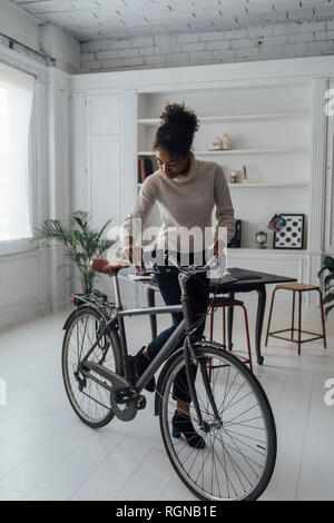 Mid adult woman leaving her home office, pushing bicycle Stock Photo