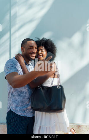 Smiling young couple embracing and taking a selfie Stock Photo