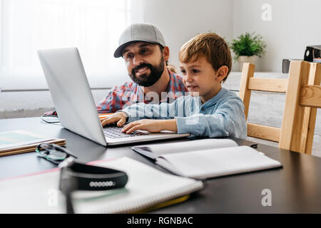 Father and son using laptop together Stock Photo