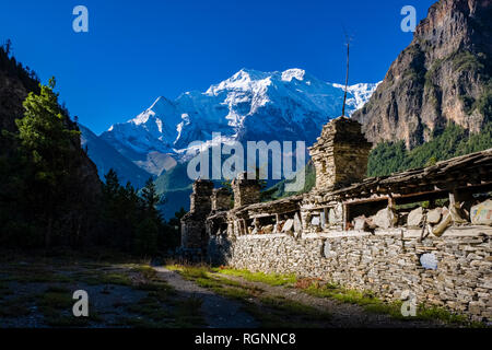 Big Mani wall in the Upper Marsyangdi valley, the snow covered summit of Annapurna 2 in the distance Stock Photo