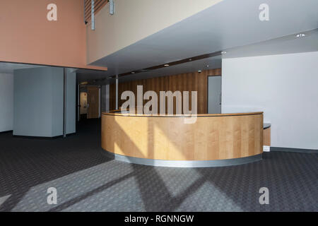 reception desk standing in an office lobby with wooden wall elements Stock Photo