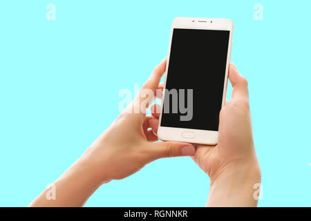 Hands holding smartphone with blank screen isolated on pastel blue background. Mobile device close up. Mock up concept Stock Photo