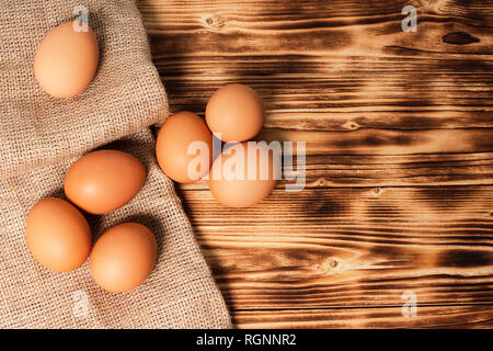 Chicken eggs on a napkin of burlap on wooden table. Top view. Rustic food background Stock Photo