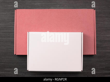 Living coral and white colors carton boxes on dark wooden desk. Copy space. Top view Stock Photo
