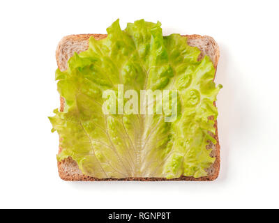Bread slice with fresh salad leaf isolated on white, clipping path. Slice of multigrain bread square form with green lettuce leaf for toast. Image of one slice wholegrain bread, top view or flat lay. Stock Photo