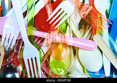 Closeup of many plastic fork and spoons in all different shapes and colors lay-ed out and photographed from above at a family party event Stock Photo