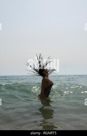 Young woman in bikini flicking hair in the sea Stock Photo