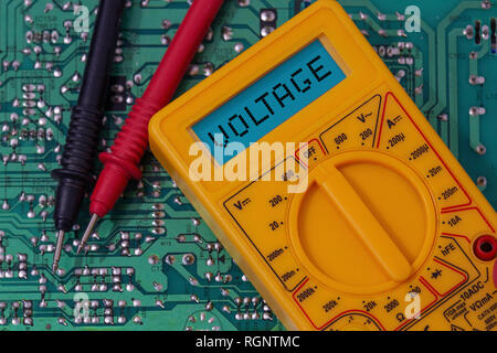 Digital multimeter multitester on a circuit board with the word voltage on the display Stock Photo