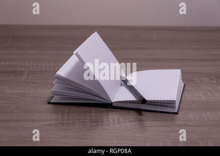 Opened notebook and pen on the brown desk. Stock Photo
