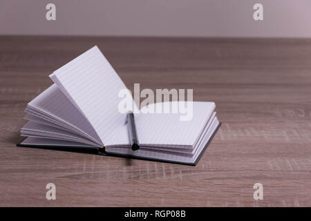 Opened notebook and pen on the brown desk. Stock Photo