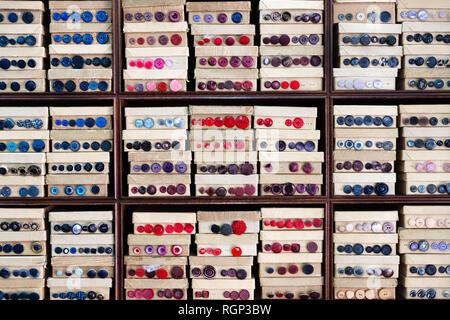 Many red and blue buttons are displayed on cartons on the sales shelf. Stock Photo