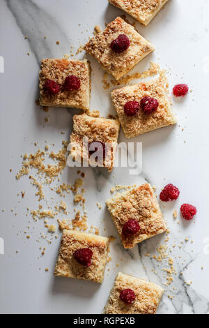 Sliced homemade cake with frozen raspberries on top on a marble background, vertical Stock Photo
