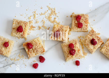 Sliced homemade cake with frozen raspberries on top on a light marble background, horizontal Stock Photo