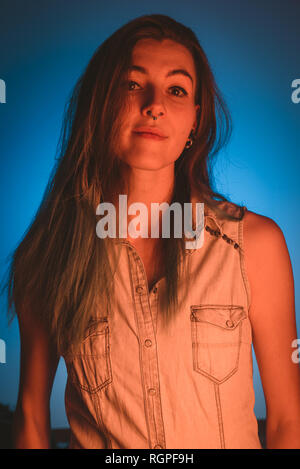 Charming young lady with piercing looking at camera in redness on blue background Stock Photo